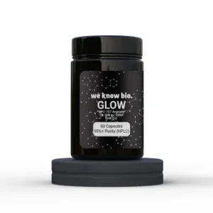 Black bottle labeled 'GLOW' on a dark starry label, perched on a circular display stand; label notes '60 Capsules' and '99%+ Purity'.